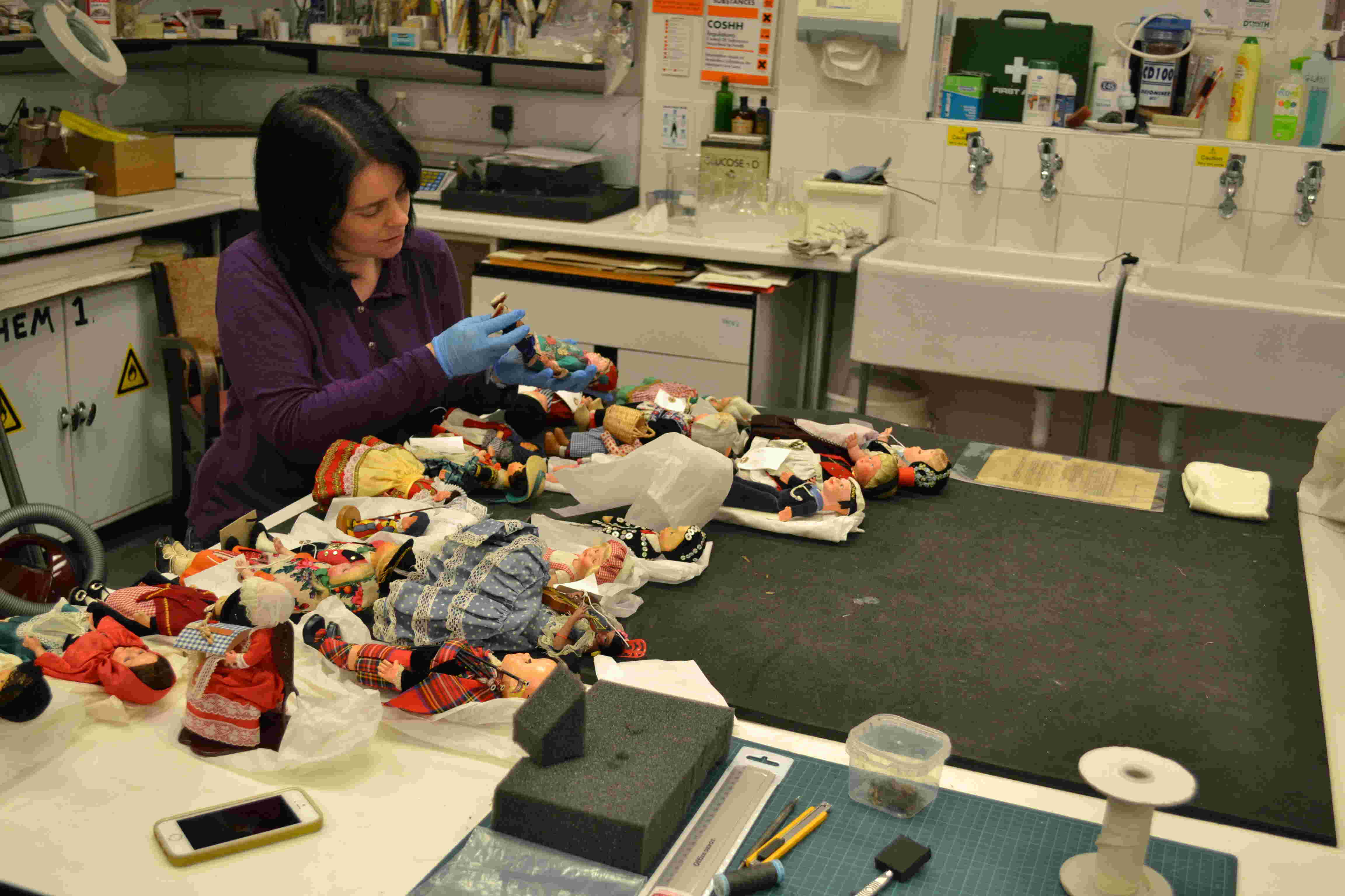 Collections Care Officer assessing costume dolls Collections Care Officer assessing costume dolls