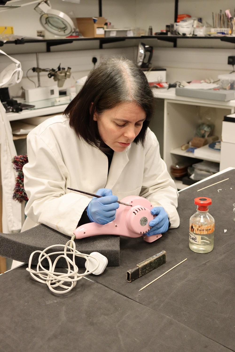 Conservator applying number to plastic object