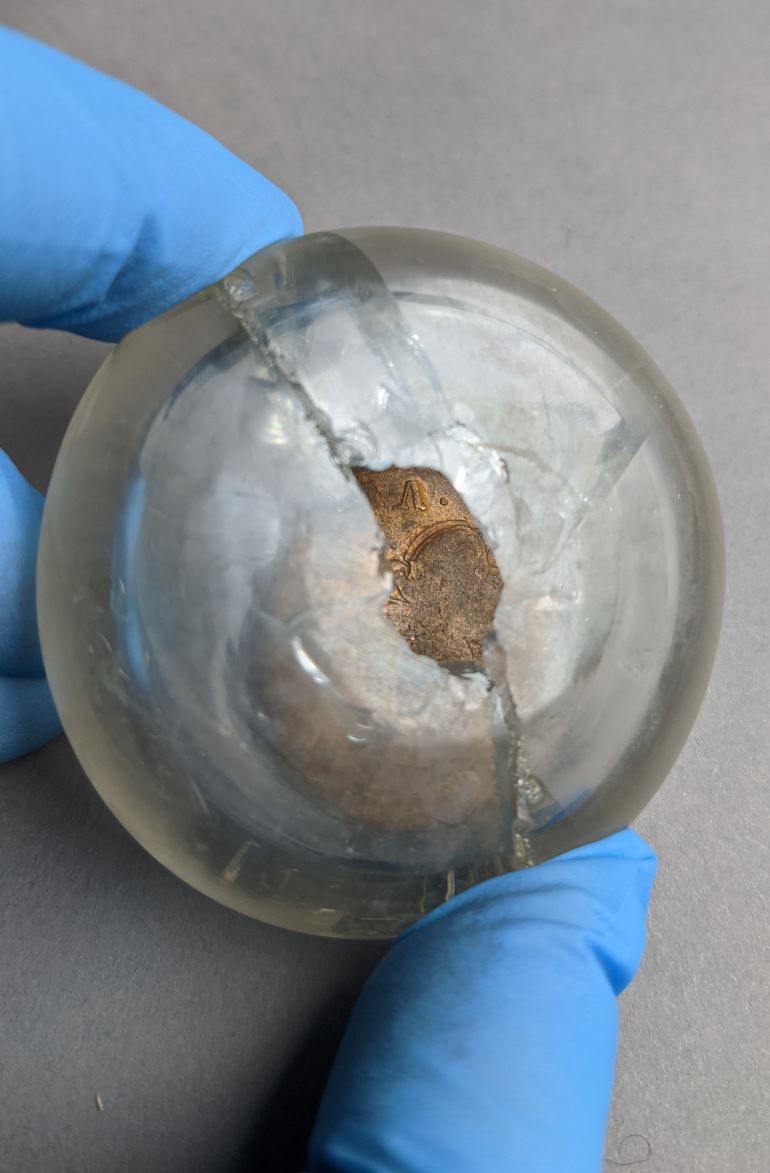 Coin from time capsule with damaged glass casing