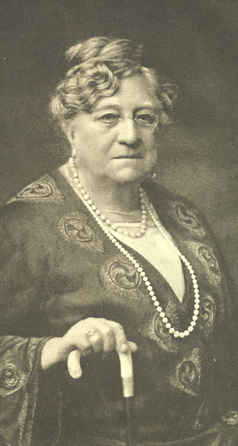 Portrait photograph of an elderly woman wearing glasses and with a walking stick