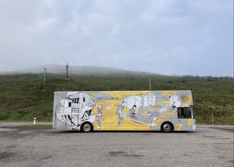 The iconic Travelling Gallery bus parked by the road with misty hills in the background
