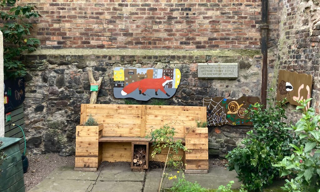 A wooden bench with a painted board behind it showing a fox
