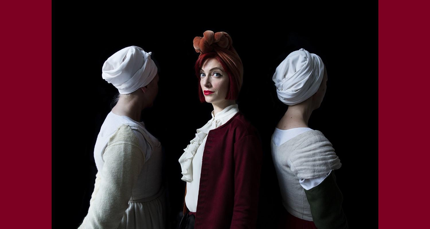 Portrait of Amber Butchart, Jane Malcolm-Davis and Ninya Mikhaila. Only the middle person's face can be seen; she is dressed in red. The other two, dressed in white and cream, have their backs to the camera