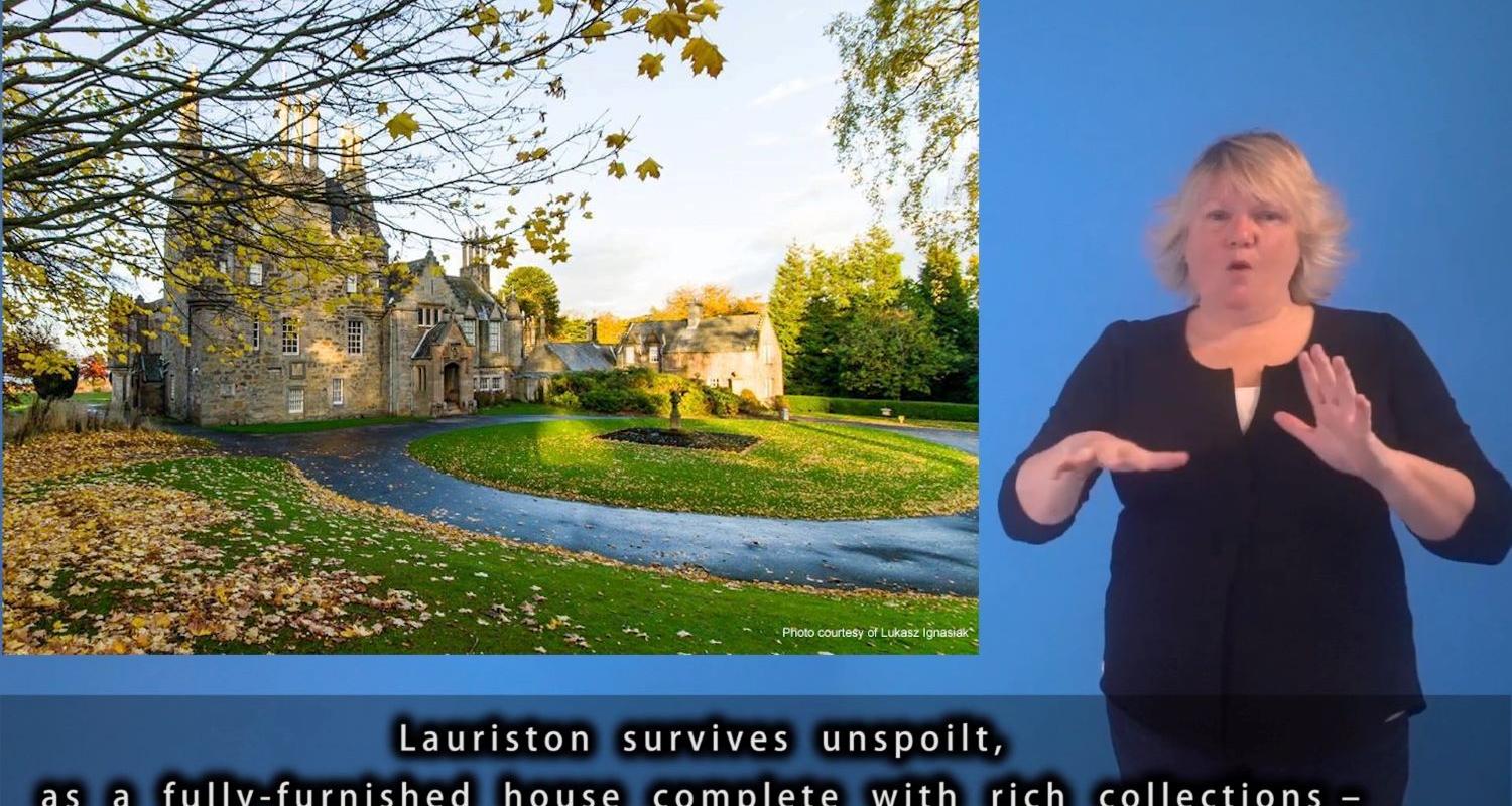 A BSL signer stands next to an image of Lauriston Castle introducing a digital tour