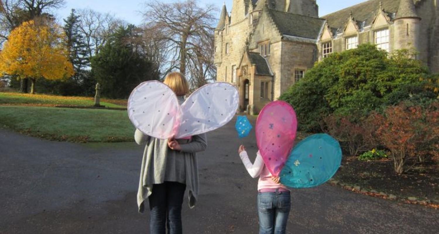 Rear view of an adult and child wearing fairy wings outside the castle