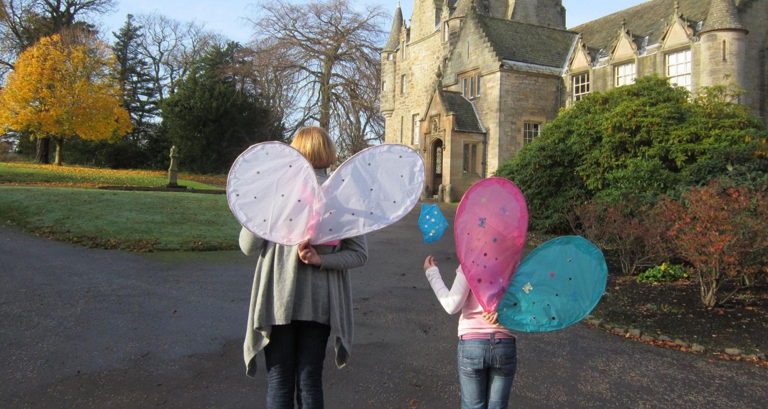 Photo of a mother and child walking towards a castle wearing fairy wings