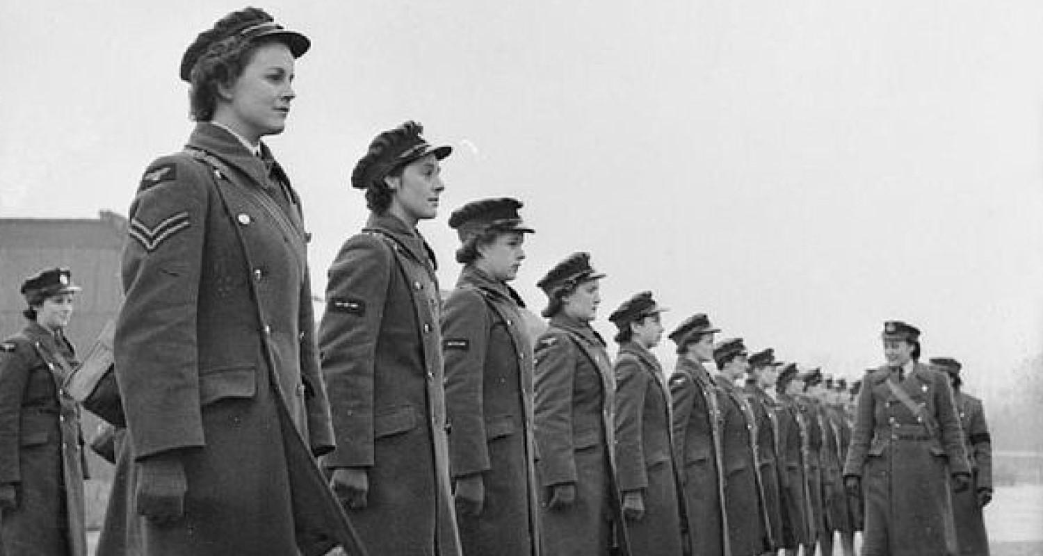 A row of women in WAAF uniforms line up for inspection at an RAF base, 1942