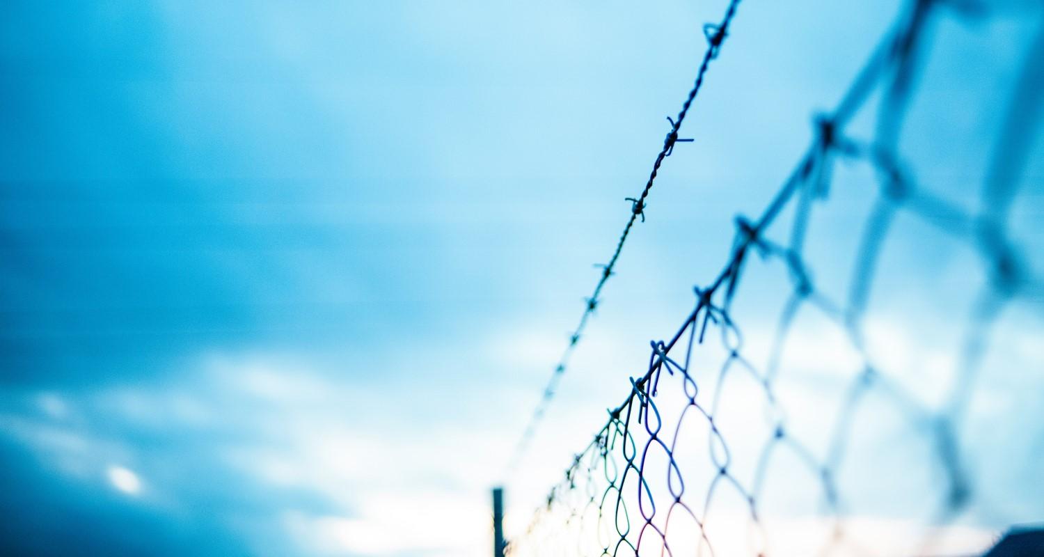 A barbed wire fence against a blue sky