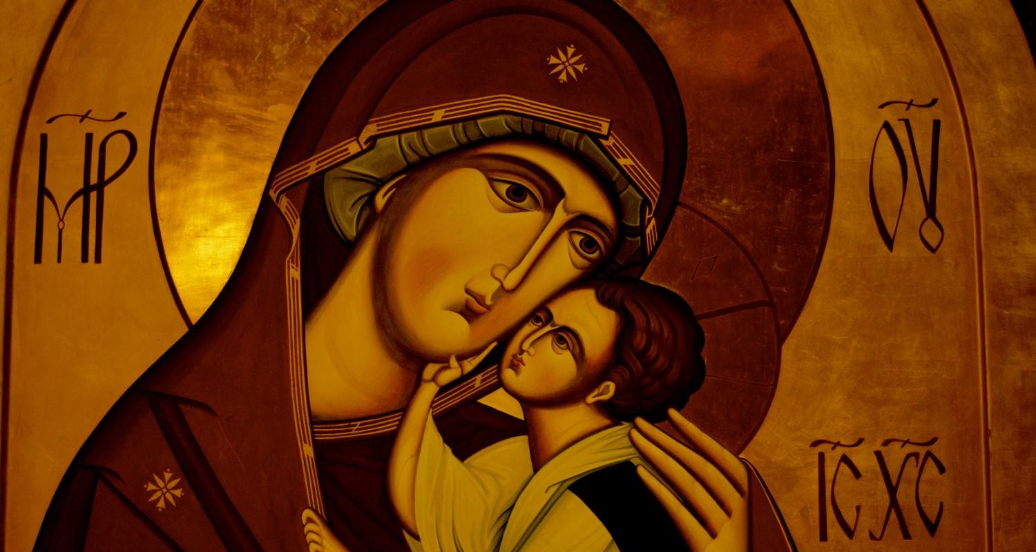 A gold-coloured image of Mary in a red and gold shawl cradling the baby Jesus