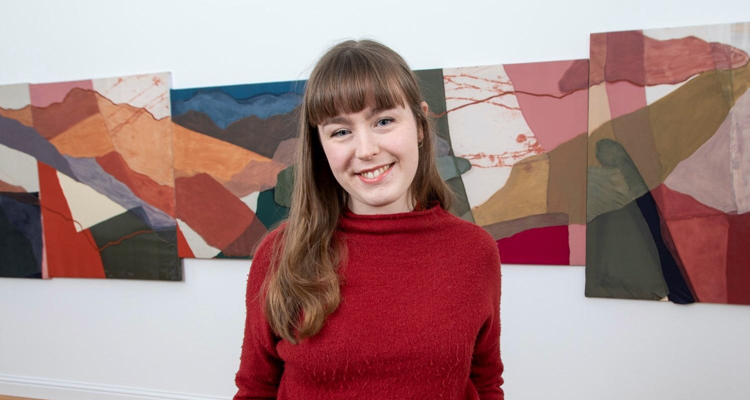 Photo of a curator standing in front of an exhibition at the Dovecot in Edinburgh