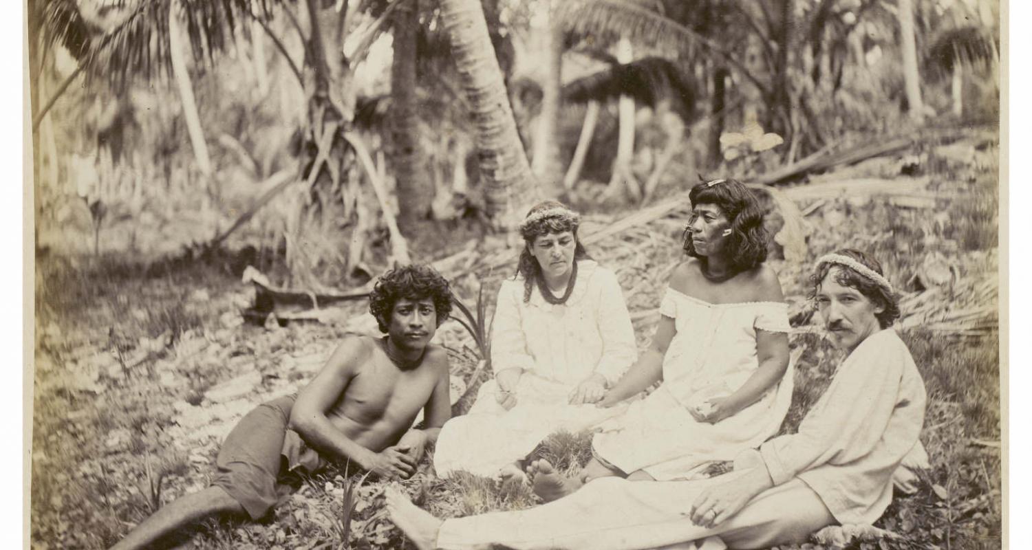 Robert Louis Stevensons in company with Nantoki and Natakauti, Butaritari. Group comprising of Nantoki, Fanny Stevenson holding hands with Natakauti, and Robert Louis Stevenson; the men are reclining, the women sitting, on the ground. 