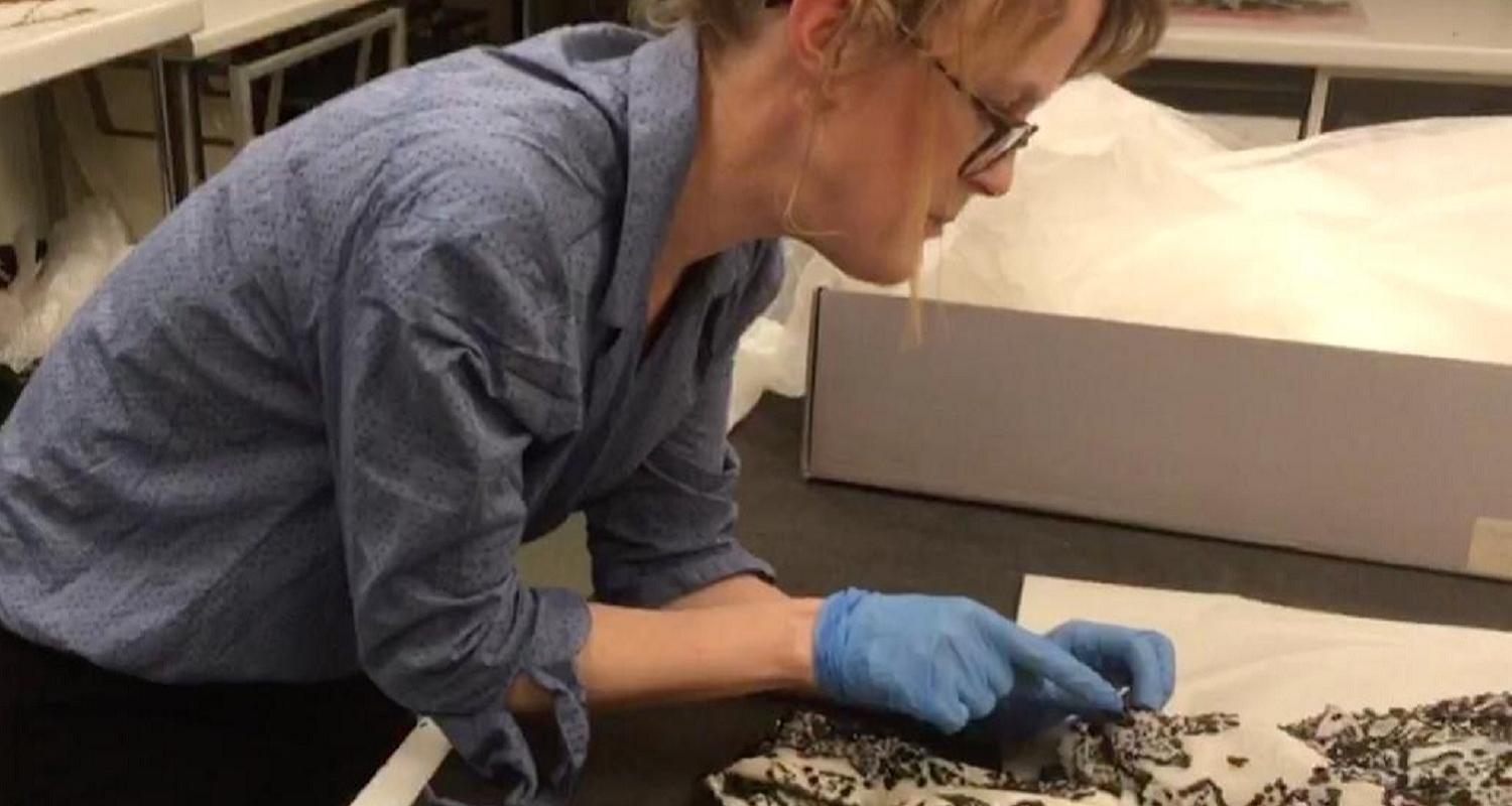 Curator Vicky Garrington sewing a label onto historic fabric