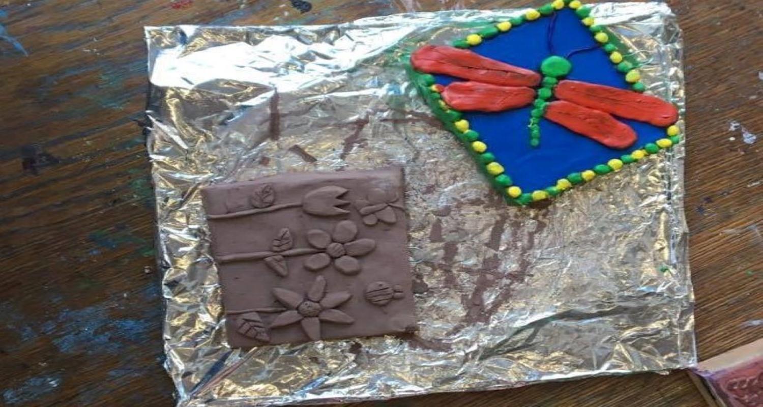 Two clay tiles, one plain with flowers, and a blue one with a dragonfly with red wings