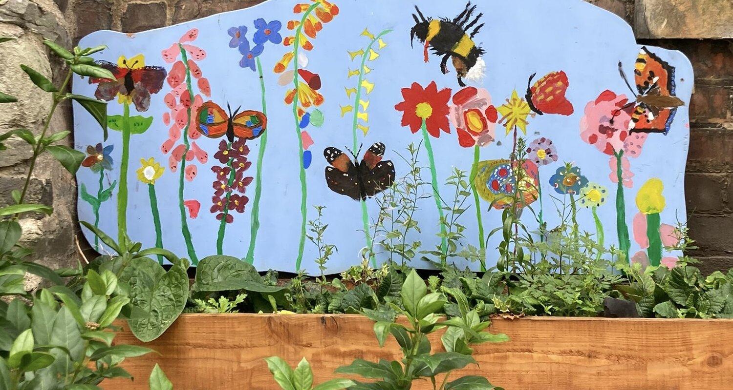 Close up image of a children's mural painting of bees, butterflies and flowers on a light blue background. 