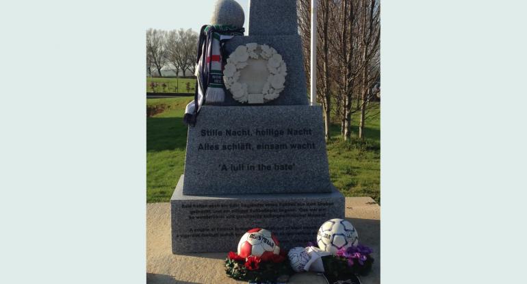 A German war memorial, with the opening lines of Silent Light, and two footballs on wreaths underneath