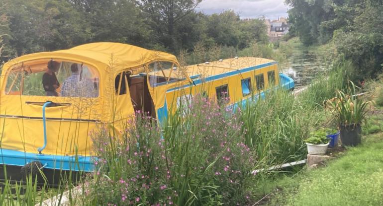 Yellow and blue long boat sitting on a canal surrounded by greenery. Part of the Museums & Galleries Edinburgh Discover Lothian project. 