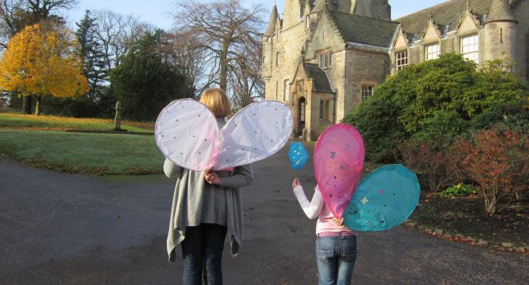 Photo of a mother and child walking towards a castle wearing fairy wings