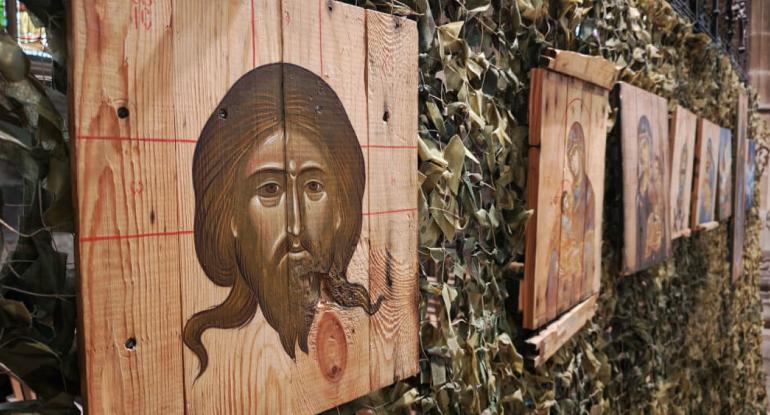 Icons on ammo boxes A row of ammo box lids with religious images on them attached to a camouflaged fence