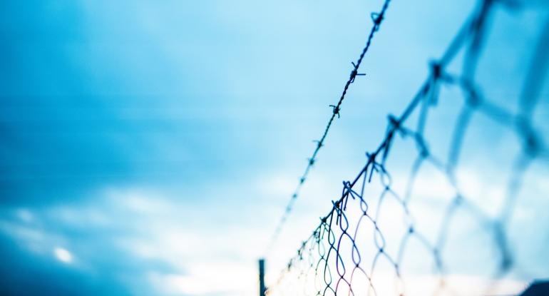 A barbed wire fence against a blue sky