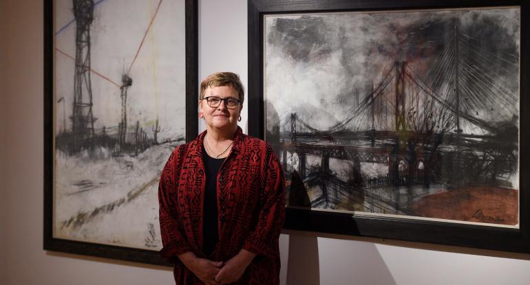 Arttist Kate Downie standing in front of her exhibited work at the City Art Centre