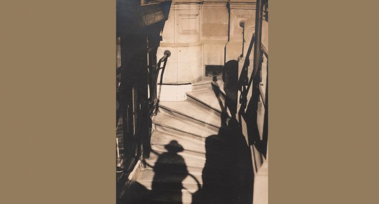 Photograph of a winding stairway with people's shadows on the stairs