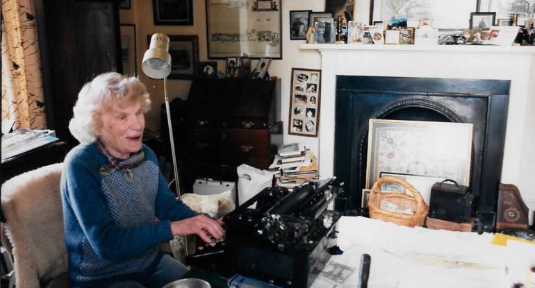 Photo of a person sitting at a table with a typewriter