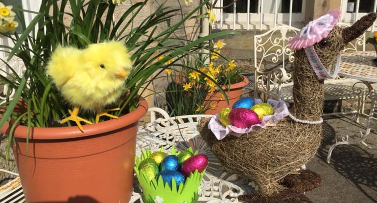 An Easter chick, a wicker duck, chocolate eggs and daffodils
