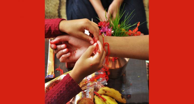 Rakhi bracelet Hands tying a rakhi - red string - bracelet onto a wrist