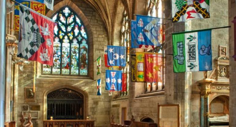 An arched window and flags flying inside St Giles Cathedral