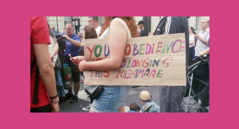 Lady holding a hand-made placard in among a big group of people 