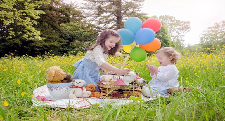2 children having a teddy Bear's Picnic in spring gardens 