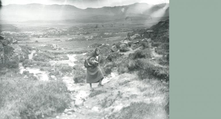Historical image of woman in remote part of Scotland carrying a bundle under her arm
