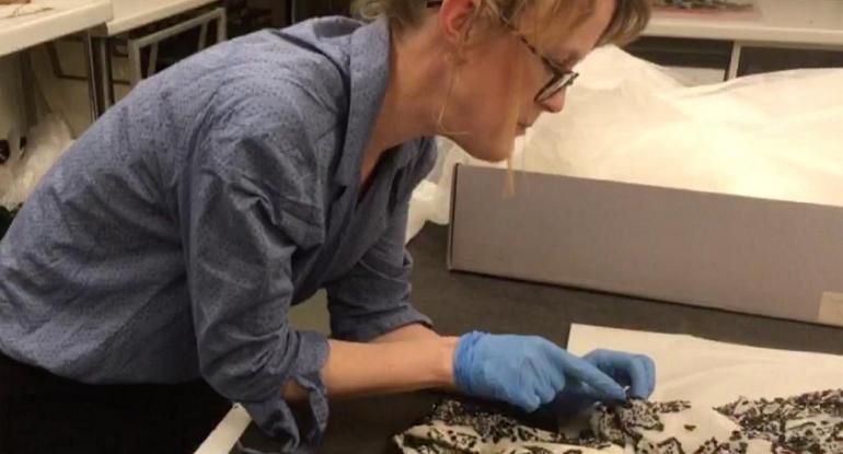 Curator Vicky Garrington sewing a label onto historic fabric