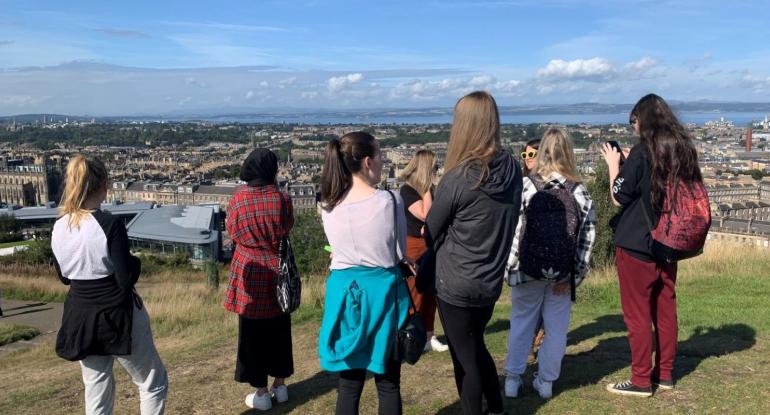 Group of  young people on Calton Hill looking over Edinburgh towards the Forth. 