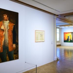 A man strolls through Edinbugh's City Art Centre, observing various paintings displayed on the walls