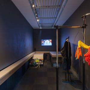 Gallery interior walls painted black. A colourful costume in red and yellow fabric hangs from a rail in the foreground 