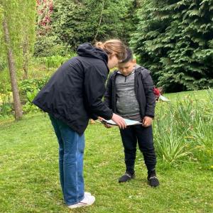 A woman and boy stand together looking at artwork on a clipboard.