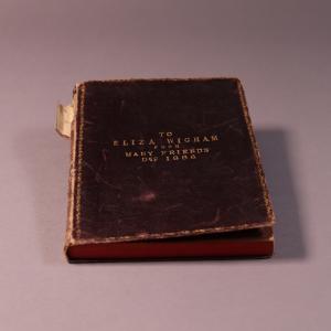 A black leather book debossed with the title " To Eliza Wigham from Many Friends Dec 1886"