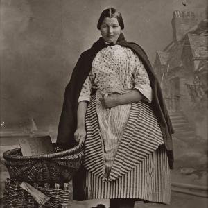 Thomas V. Begbie, Studio portrait of Newhaven fishwife, standing beside wicker creels, plate negative: c. 1857-1860 The Cavaye Collection of Thomas V. Begbie Prints. City Art Centre, Museums & Galleries Edinburgh