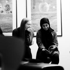 Two people sitting together smiling in a gallery space