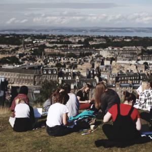 A group of people sitting on Calton Hill drawing in sketch books