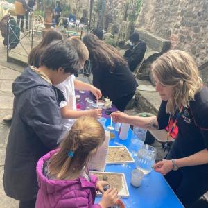 Children standing at a table with Dynamic Earth staff behind showing them how to take part in activities