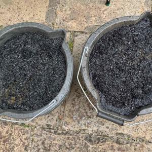 Two black buckets shown from above, filled with biochar