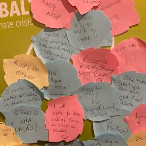Colourful post-it notes stuck to a panel with hand written pledges made by visitors.